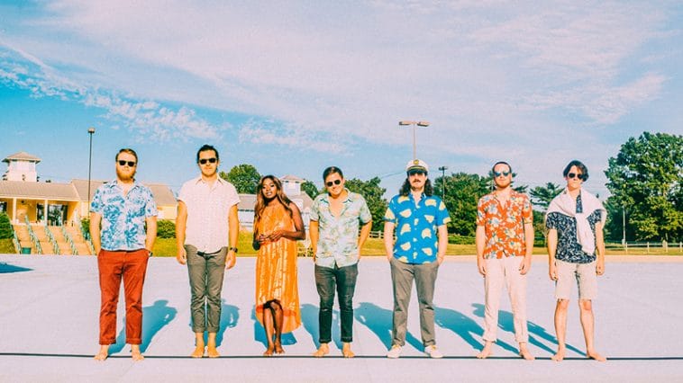 Music band LUTHI has seven members lined up in brilliant spring colors in a parking lot