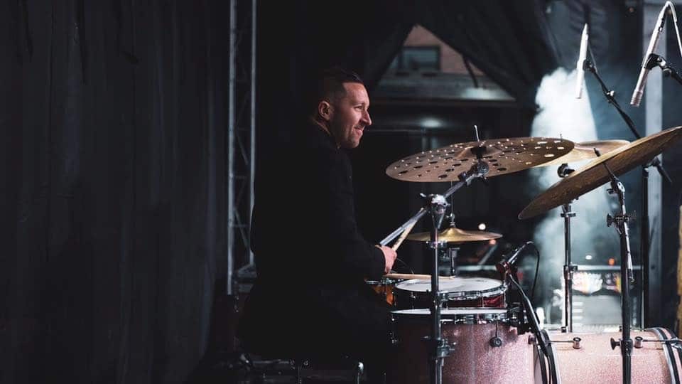 Drummer man smiling in front of expensive drum set