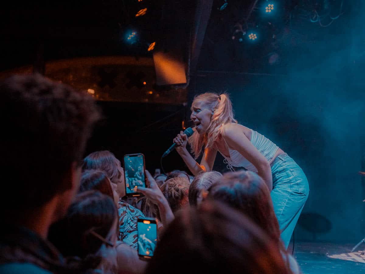 Maude Latour bends over the crowd to sing while the crowd takes pictures
