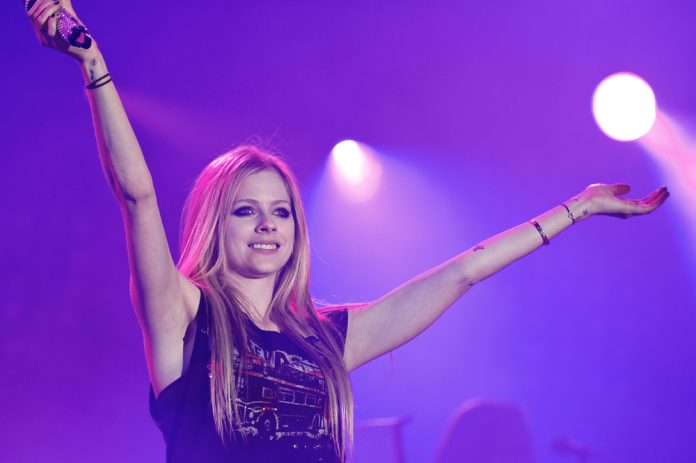 singers who look young singers who suffer from a disease avril lavigne holding her arms up in concert