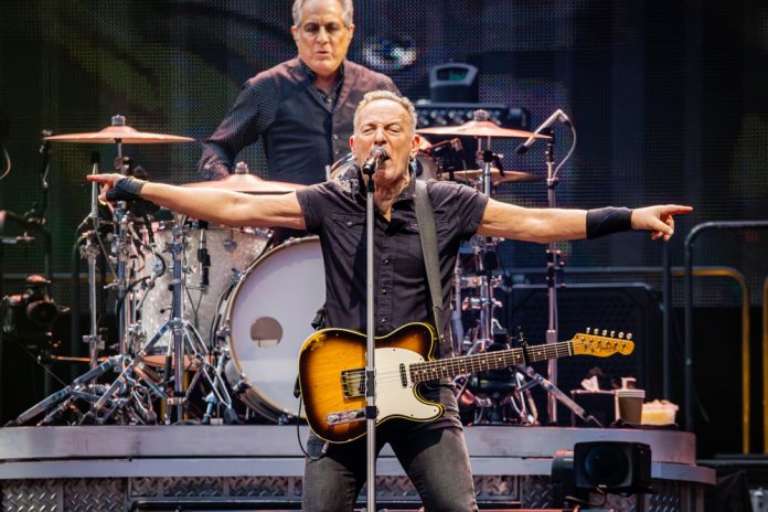 highest earning tours in 2023 bruce springsteen's net worth bruce springsteen on stage wearing a guitar with his arms held out