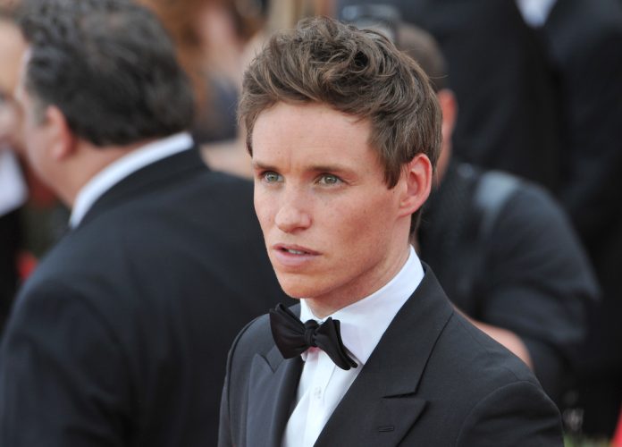 eddie redmayne in a suit in a crowd