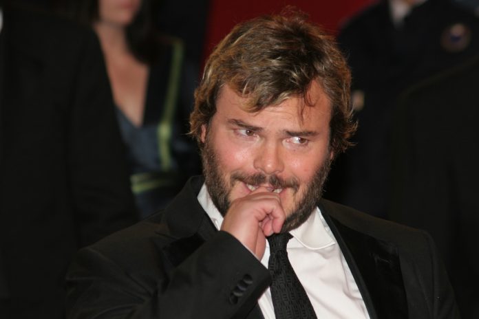 jack black in a suit with his finger near his mouth