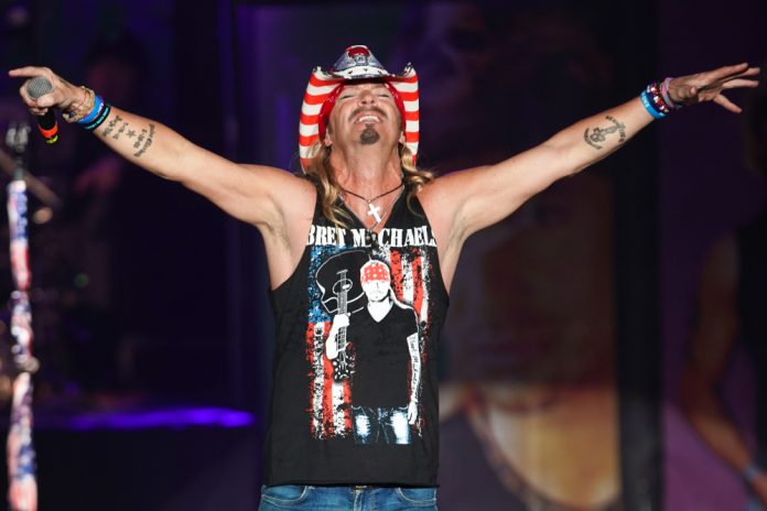 bret michael's net worth bret michaels standing on stage with his arms out toward the crowd