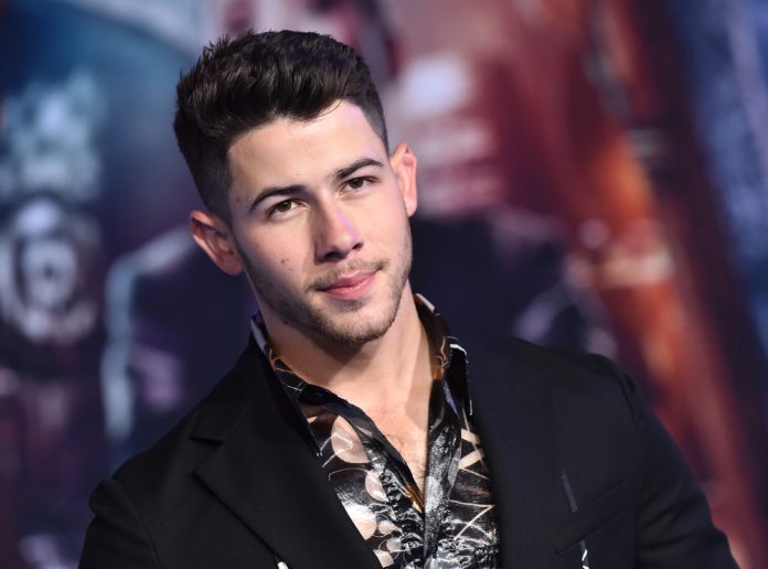 nick jonas' net worth image of nick jonas in a black outfit in front of a blurred background