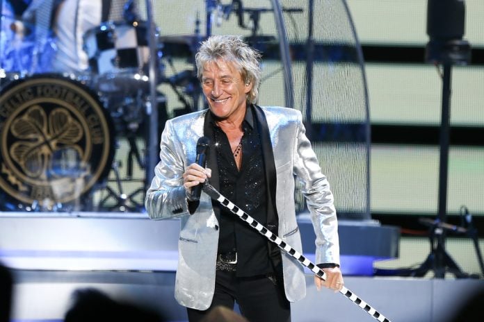 rod stewart on stage in a silver suit holding a microphone