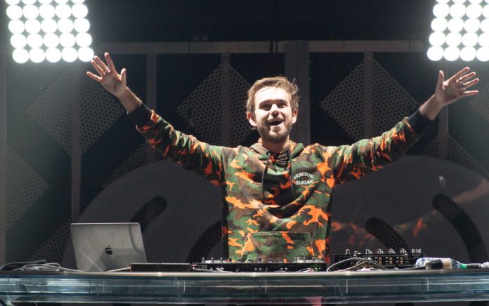 zedd the edm DJ on stage in a green and orange camo shirt