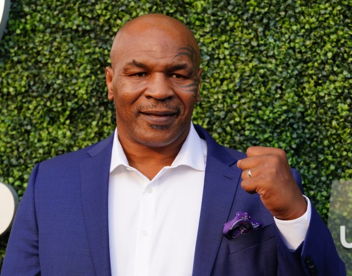 celebrities who went bankrupt mike tyson in a suit holding his fist up