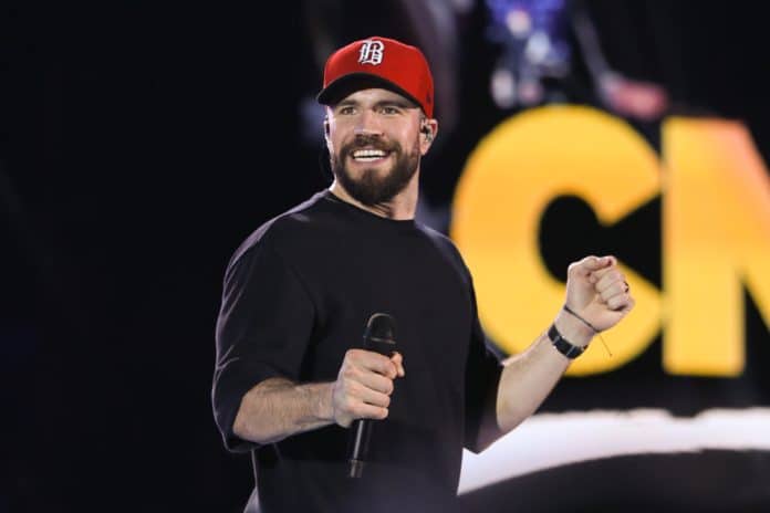 tallest country singers sam hunt in a long sleeve shirt and baseball cap performing on stage