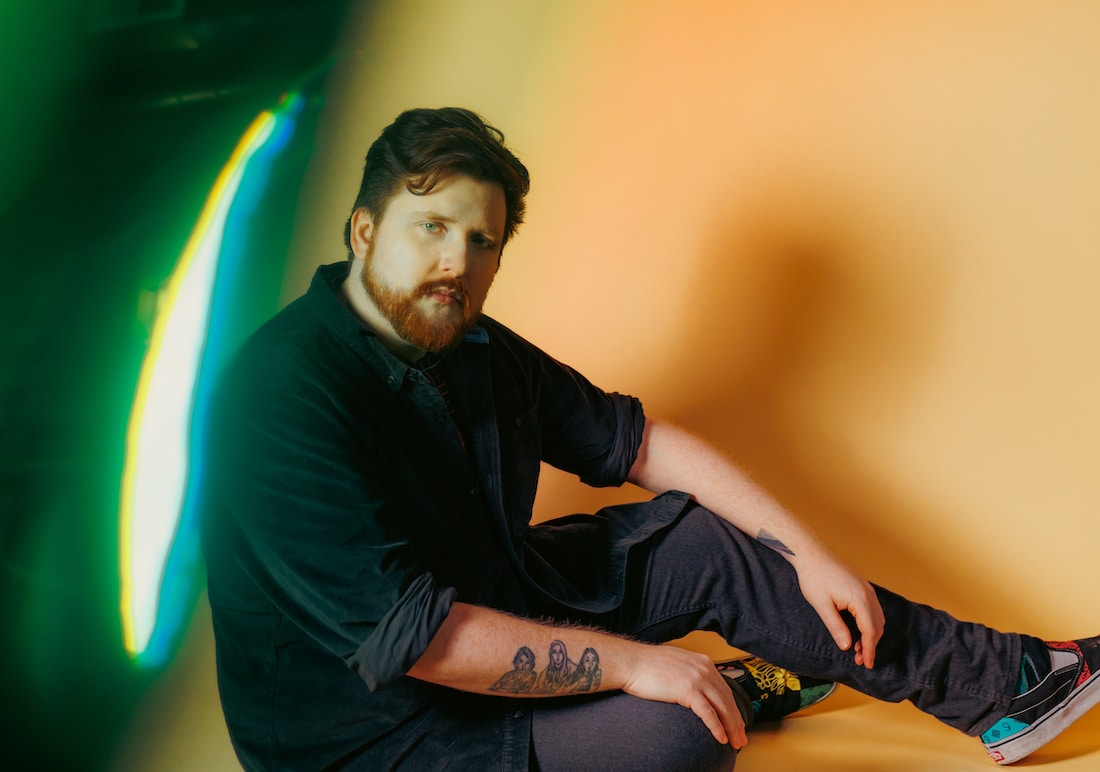Artist Sache mullin sitting down in a photography studio