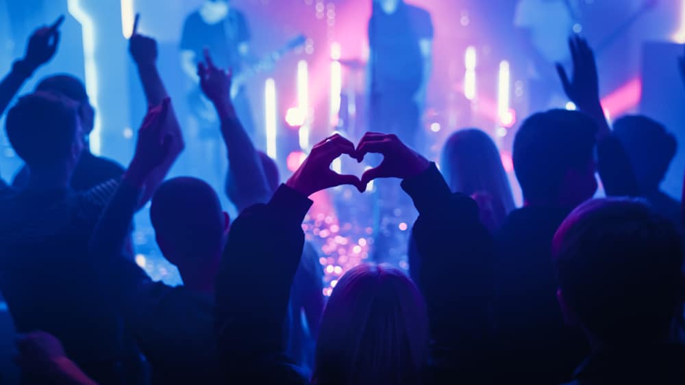 tall musicians a concert with a fan holding their hands in a heart shape