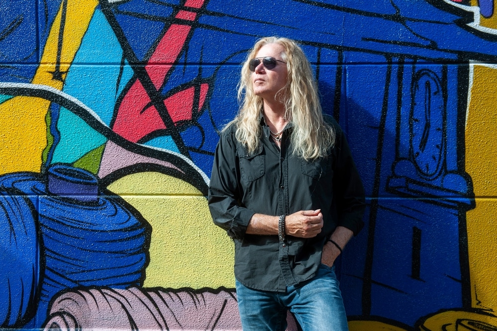 tall musicians adrian vandenberg leaning against a graffiti wall