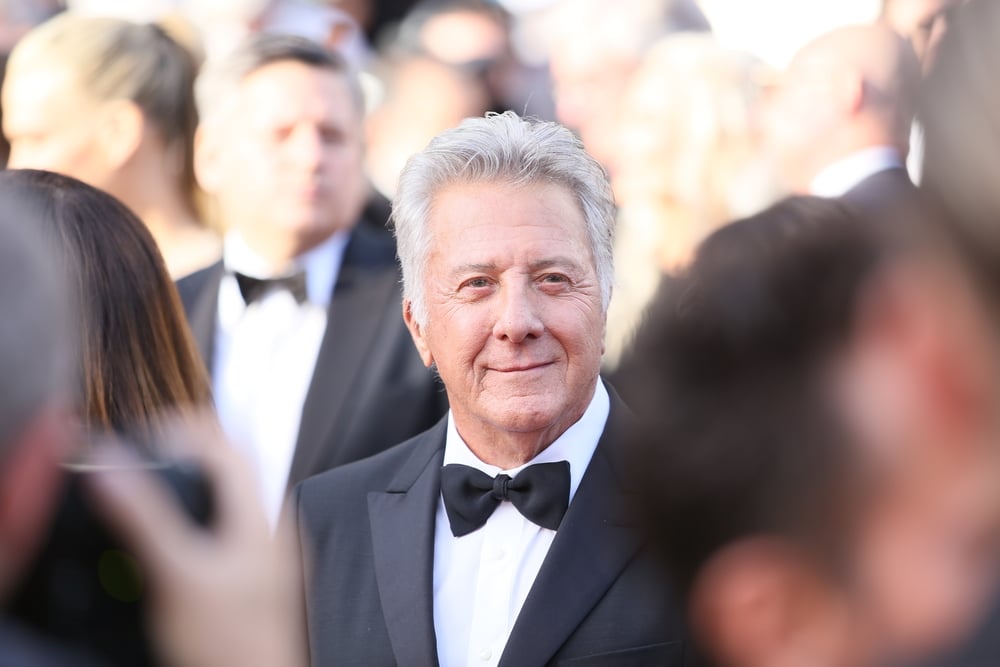 dustin hoffman in a suit arriving at an event in a crowd
