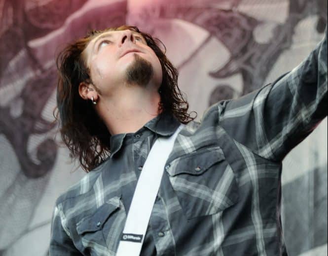 tall musicians jim root on stage in a plaid shirt looking up