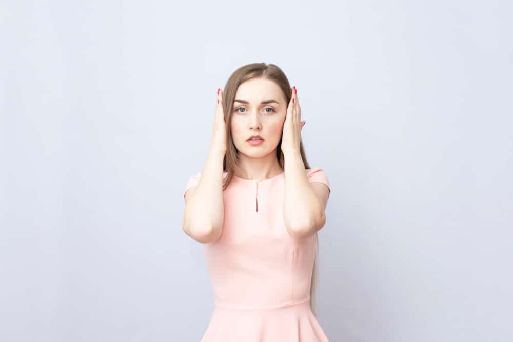 are concerts bad for your ears? a woman covering her ears in a pink dress