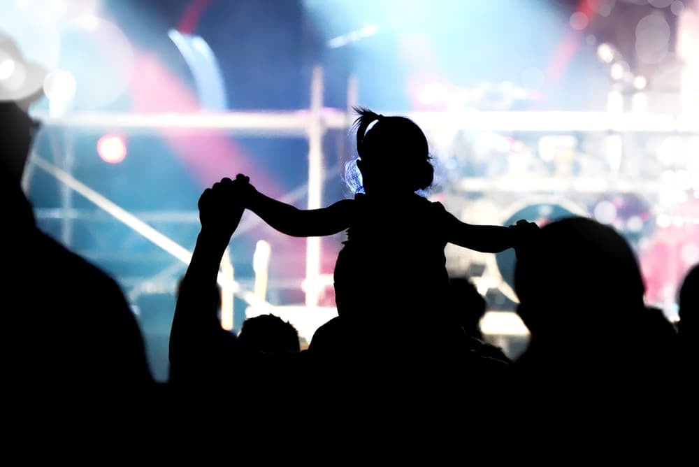 can you take a baby to a concert? a man with a kid on his shoulders at a concert
