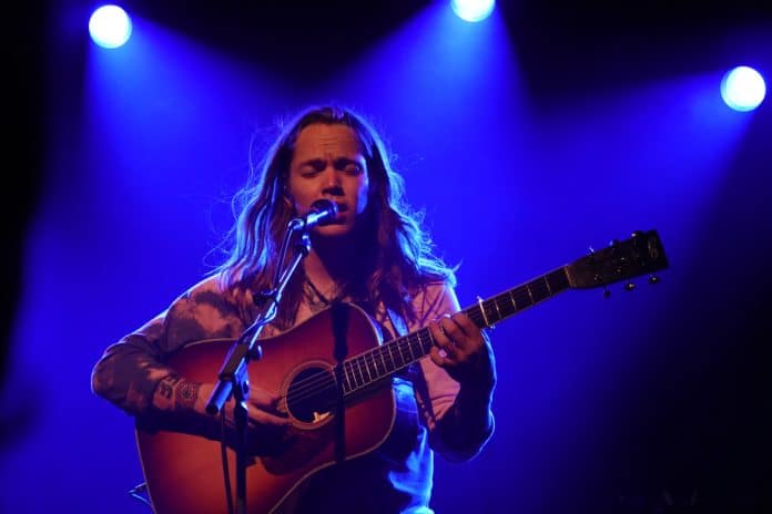 billy strings playing guitar on stage