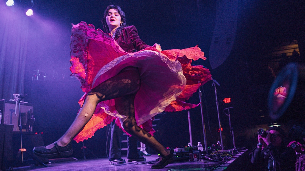 Performer dancing on stage in a twirl, with her red and pink skirt billowing out.