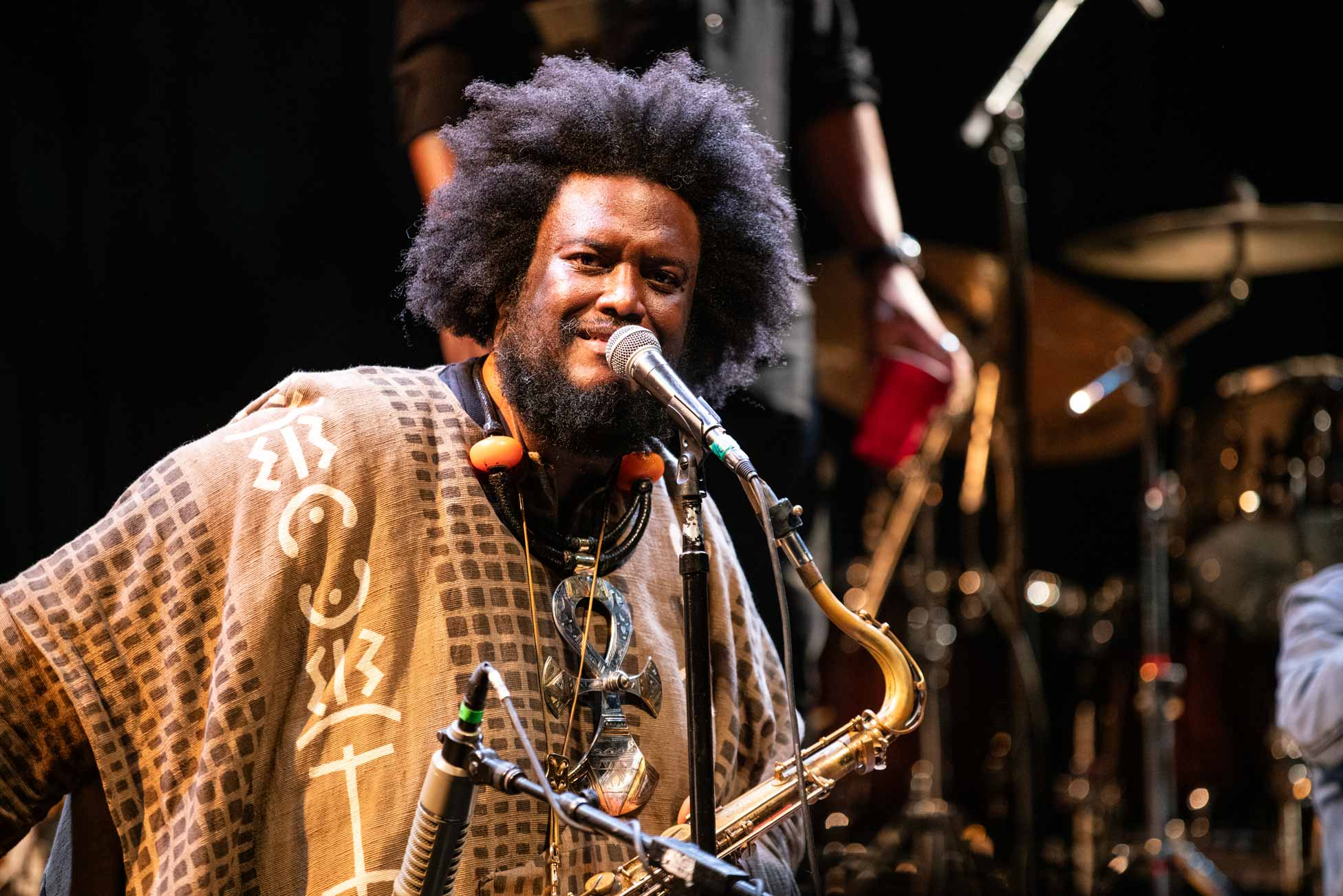 Singer and saxophonist looks at the audience from the stage while leaning into the microphone.